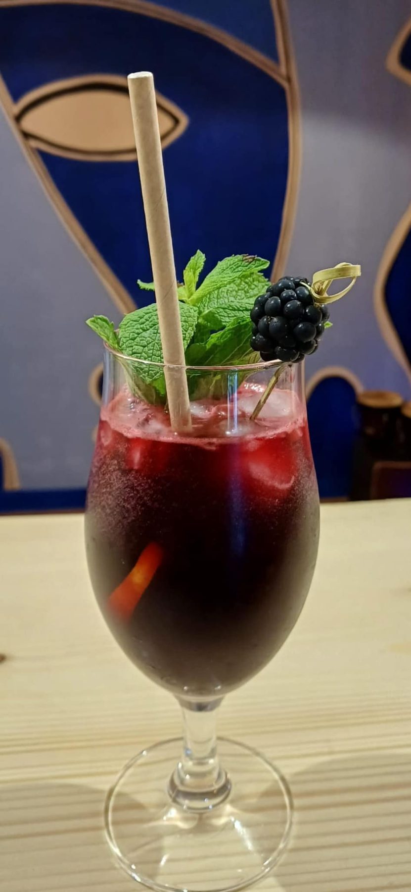 Un cocktail rouge garni d'une mûre, dans un verre à pied