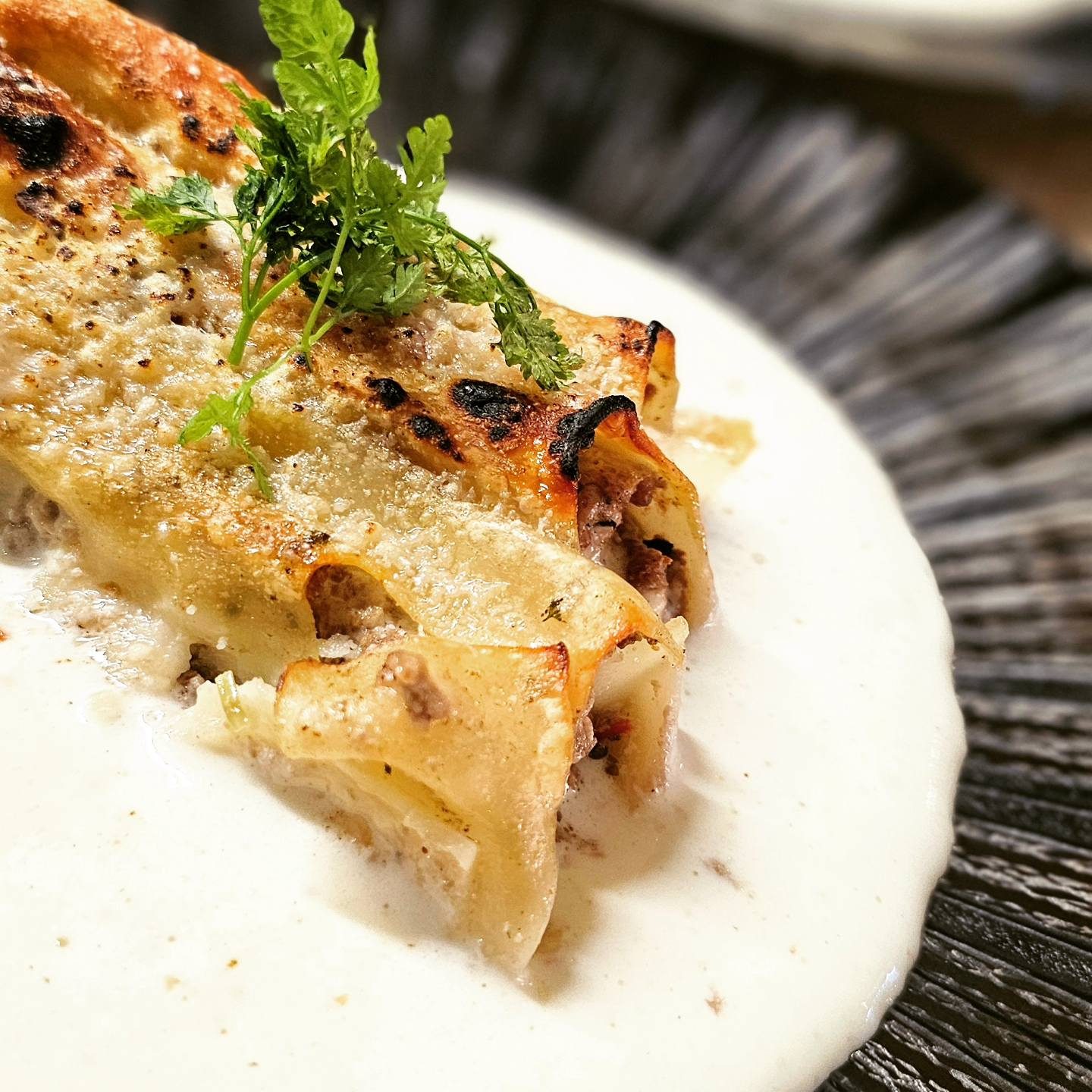 Des pâtes fourrées gratinées sur une crème blanche, avec des herbes fraîches